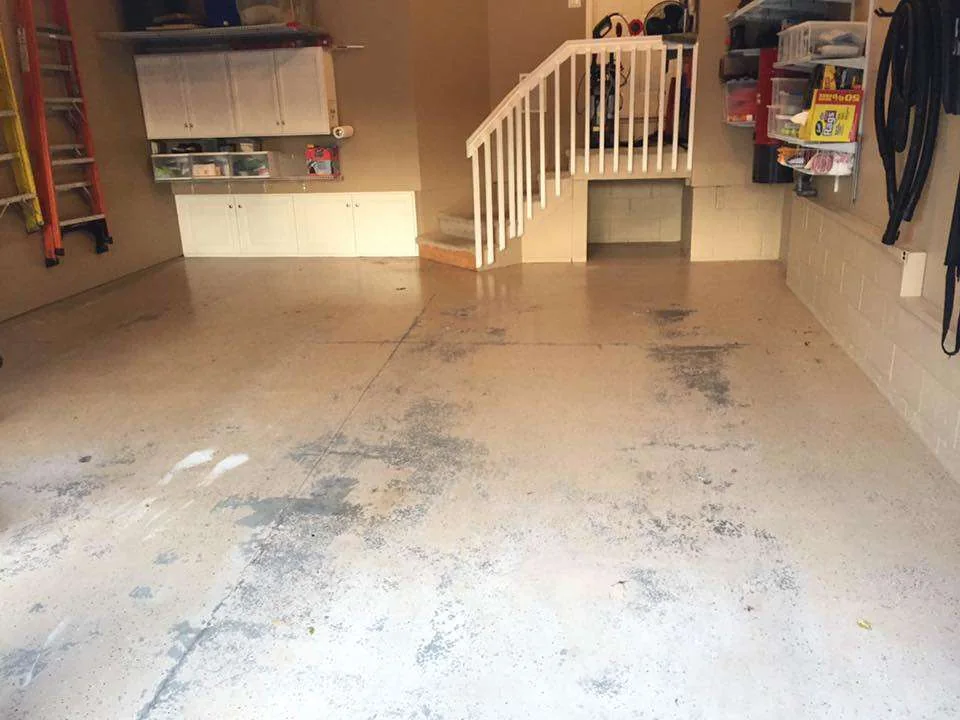 Before: a garage with stained, bare concrete and a staircase.