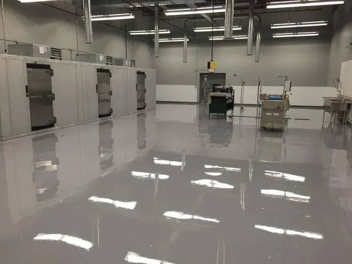 Commercial kitchen with stainless equipment on a glossy gray coated floor.