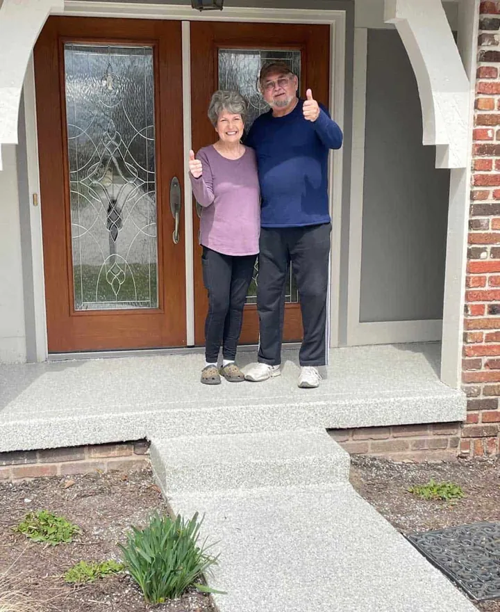 Couple giving a thumbs up on their newly coated front porch.