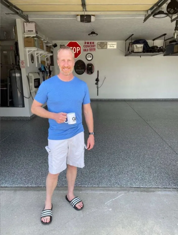 Homeowner holding a Galaxy mug in his garage on a new flake floor.
