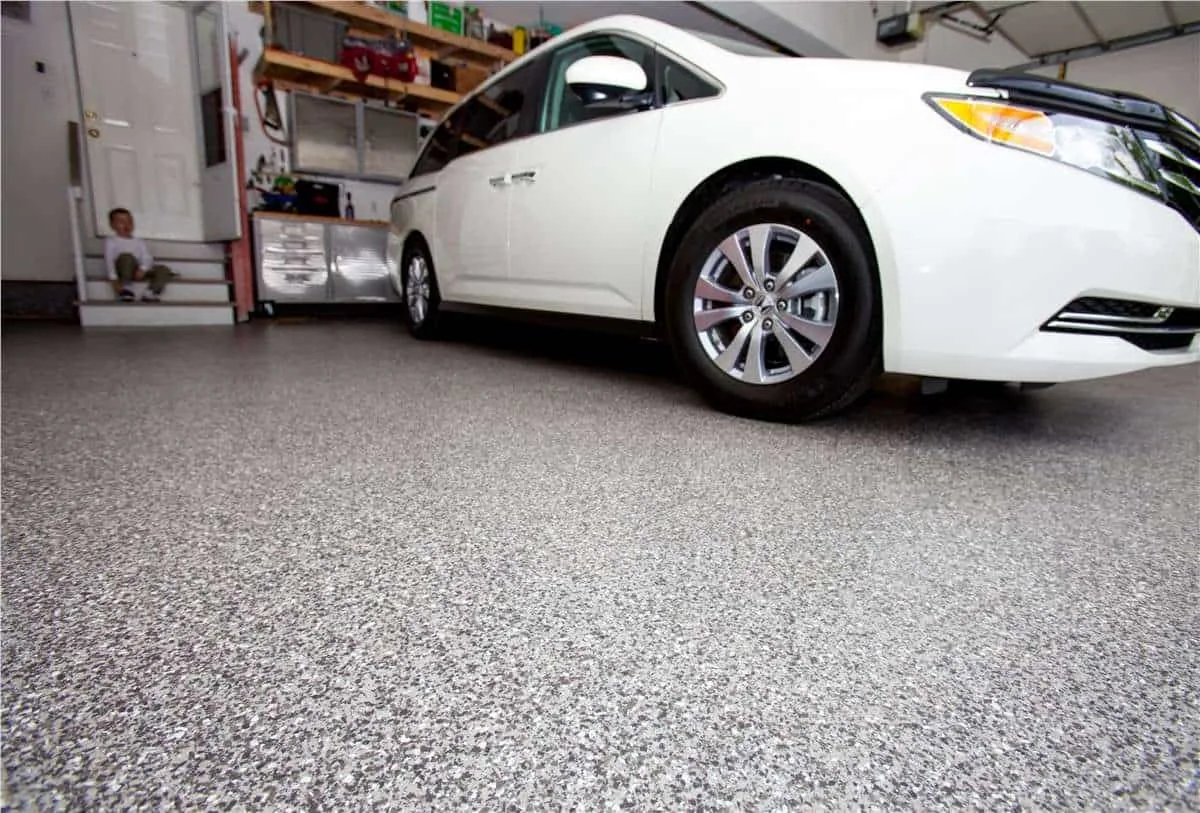 White minivan parked on a gray flake garage floor beside a workbench.